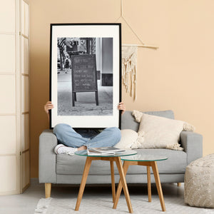 Love your enemies sign in focus with a New York pedestrian blurred behind it