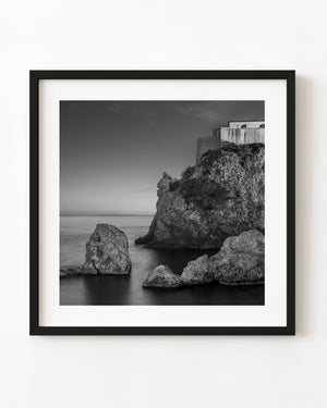 Lovrijenac Fortress above rocky Dubrovnik coast and smooth sea at dusk in black and white