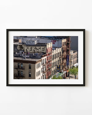 Lower Manhattan rooftops with graffiti, red fire escapes and sunlit brick buildings