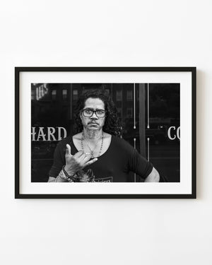 Black and white street portrait of man making hand gesture in Lower Manhattan