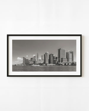 Lower Manhattan skyline across the East River with a passing boat in black and white