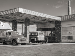 Ludlow fire district truck beside old vehicles and a boarded service station