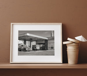 Black and white Americana photograph of old trucks and a worn garage frontage