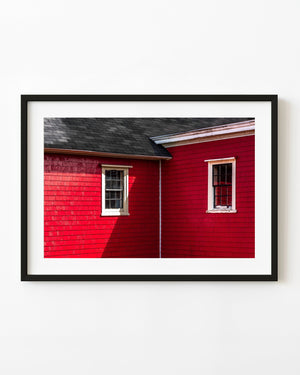 Two white-trimmed windows on a red shingled house in Lunenburg