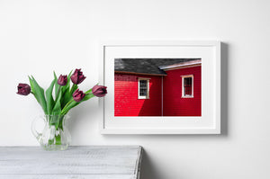 Architectural detail of two windows beneath a dark shingled roof in Lunenburg