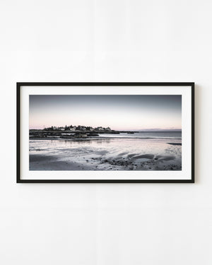 Maine coastal houses above a rocky beach beneath a pastel evening sky