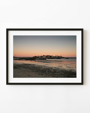 Maine coastal village at sunset beside a rocky shoreline