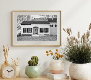 Monochrome architectural photograph of a clapboard house and flag-draped door