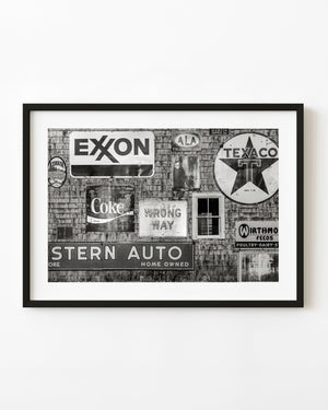 Black and white photograph of vintage Texaco and Exxon signs on shingle wall in Maine