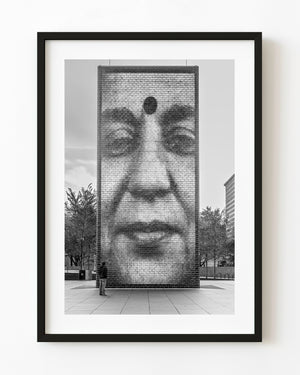 Black and white photograph of a man facing a giant portrait at Chicago’s Crown Fountain