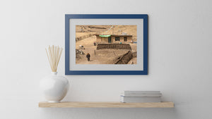 Dry hillside village in China with prayer flags, grazing animals and a man on the path