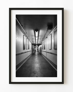 Black and white photograph of a man walking through a New York station passage