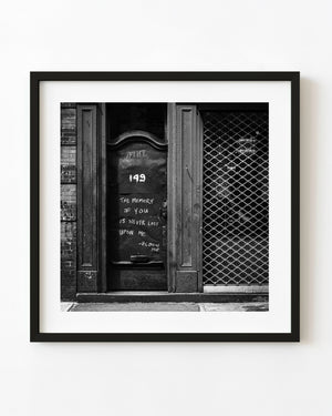 Black and white photograph of a weathered Manhattan door with a handwritten memory message