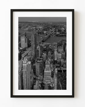 Black and white aerial photograph of Manhattan towers and bridges across the East River