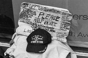 Black and white photograph of a Vietnam Veteran cap beneath a handwritten plea in Manhattan