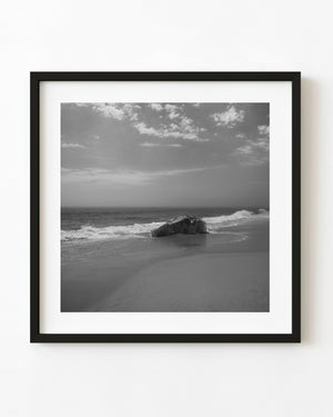 Black and white Martha’s Vineyard beach with a single boulder amid breaking waves