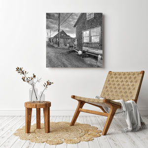 Monochrome village scene with shingle siding, barrels and a gravel road