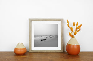 Monochrome seascape with smooth wet sand and rocks along the surf line