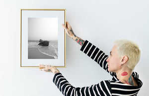 Dark shoreline rocks contrast with pale fog and white wave foam