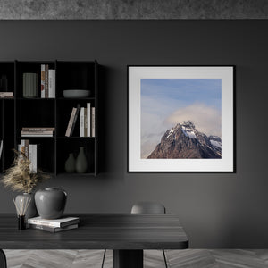Square mountain photograph with dark ridges, white snow and soft sky