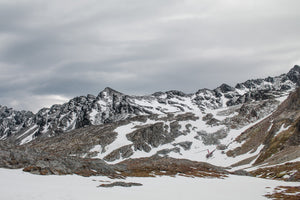 Snowy Martial Mountains and a distant helicopter beneath an overcast sky