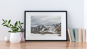 A small helicopter crosses a snow-covered valley in the Martial Mountains