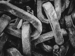 Dramatic interplay of light and shadow on colossal chains, showcasing their formidable strength and size.