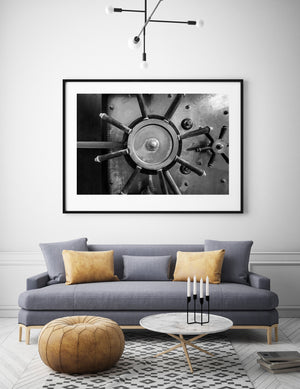 Large and small spoked wheels on a steel vault door in black and white