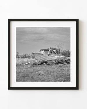 Weathered wooden boat named Memories rests on land in black and white