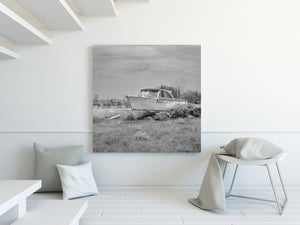 Monochrome photograph of a cabin boat stranded in an overgrown field