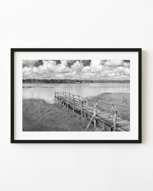 Black and white Mexican wetland landscape with a wooden pier and billowing clouds