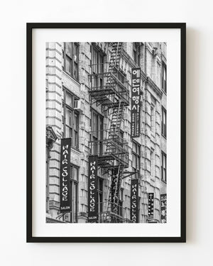 Black and white photograph of Midtown Manhattan fire escapes and vertical signs