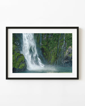 Waterfall cascading down steep rock face in Milford Sound New Zealand