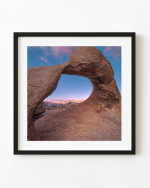 Mobius Arch frames sunlit Eastern Sierra peaks beneath a blue and pink sky