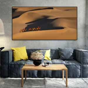 Golden sand dunes and deep curved shadows surround Mongolian camel riders