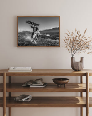 Eagle with extended wings above horseback hunter in rugged landscape