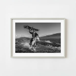 Eagle hunter riding a horse through a river in Khovd Province Mongolia