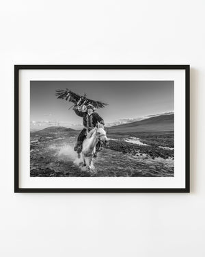 Eagle hunter riding a horse through a river in Khovd Province Mongolia