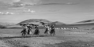 Kasachische Reiter reiten mit Adlern in der Wüste Gobi