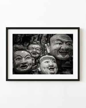 Black and white still life of painted Mongolian masks with expressive faces