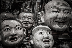 Several weathered masks display open mouths and carefully painted eyes
