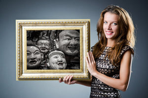 A large smiling mask rises behind smaller faces in monochrome