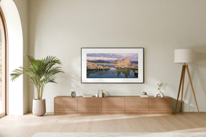 A large tufa formation rises beside still water beneath pastel clouds