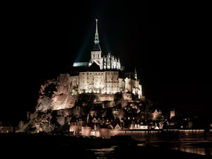 Warm lights reveal stone walls and rooftops below the abbey spire