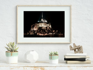 Floodlit Gothic architecture crowns the rocky island at night