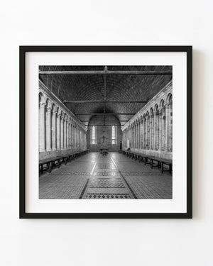 Black and white interior of Mont Saint-Michel refectory with stone columns and a timber ceiling