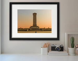 The monument stands at the centre of a quiet paved square at sunset