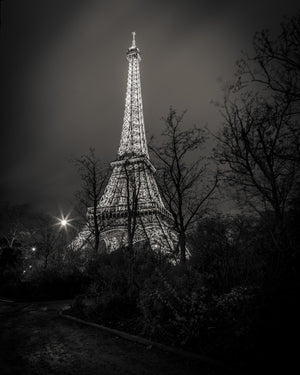 Moody monochrome photo of the Eiffel Tower lit in a foggy Paris evening