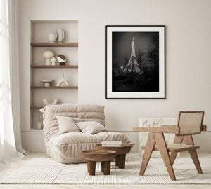 Illuminated Eiffel Tower seen through a dark forested pathway at night