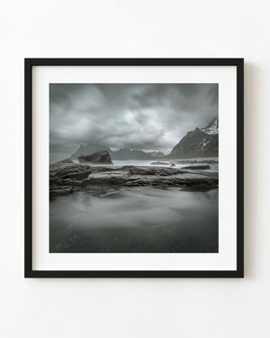 Moody Norwegian seascape with layered shoreline rocks and distant mountains